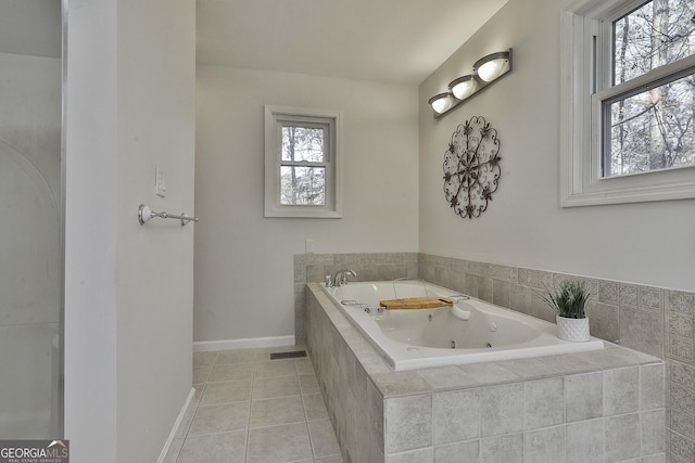 bathroom featuring tiled tub, plenty of natural light, and tile patterned flooring