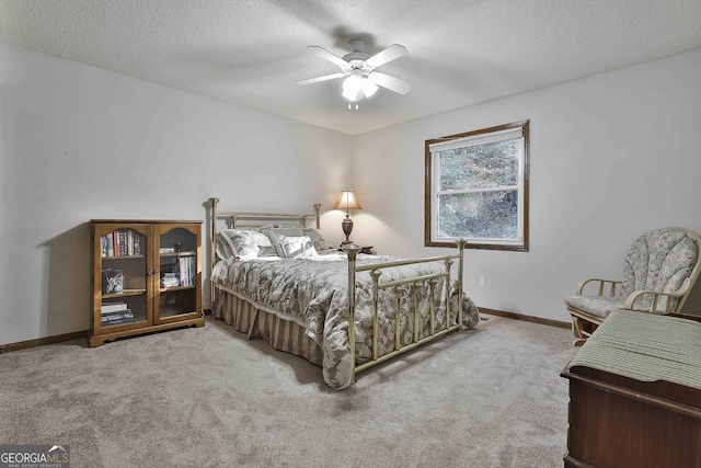 bedroom with ceiling fan, carpet floors, and a textured ceiling