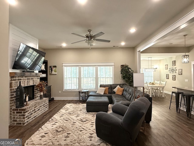 living room with ceiling fan, dark hardwood / wood-style floors, and a brick fireplace