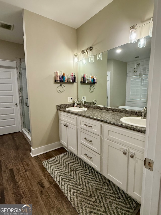 bathroom with hardwood / wood-style flooring, vanity, and a shower with door