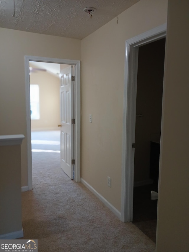 corridor featuring light colored carpet and a textured ceiling