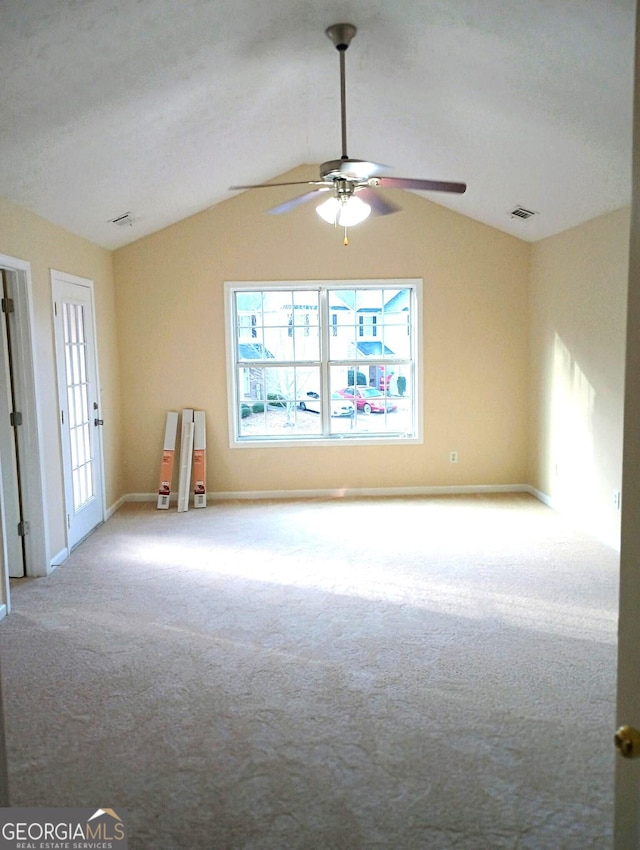 carpeted spare room with ceiling fan and vaulted ceiling