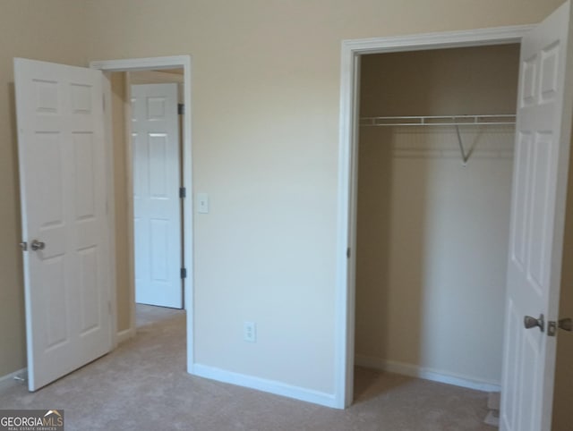 unfurnished bedroom featuring light carpet and a closet