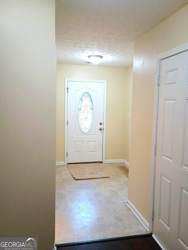 foyer entrance with a textured ceiling and baseboards