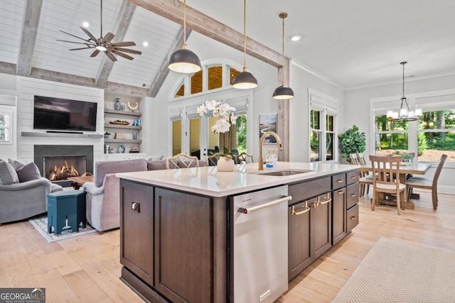 kitchen featuring sink, a fireplace, an island with sink, decorative light fixtures, and dark brown cabinets