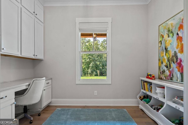 office space featuring built in desk, dark hardwood / wood-style flooring, and crown molding