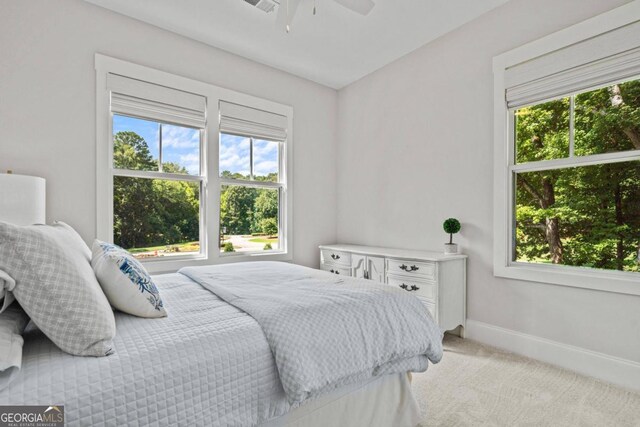 carpeted bedroom featuring ceiling fan and multiple windows