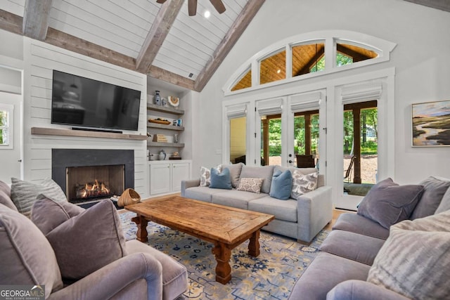 living room with ceiling fan, built in features, beamed ceiling, high vaulted ceiling, and a fireplace