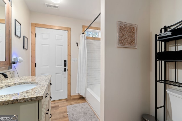 full bathroom with hardwood / wood-style floors, vanity, toilet, and shower / tub combo with curtain