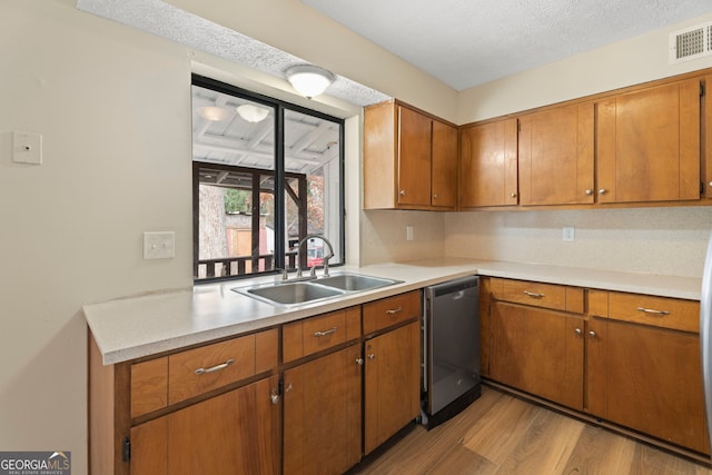 kitchen featuring sink, stainless steel dishwasher, a textured ceiling, and light hardwood / wood-style flooring