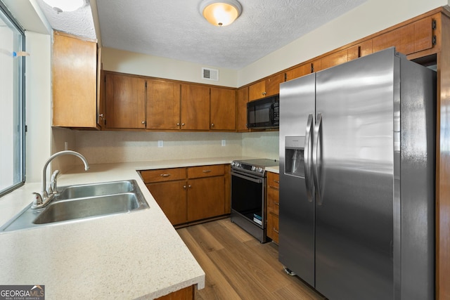 kitchen with stainless steel appliances, dark hardwood / wood-style flooring, sink, and a textured ceiling