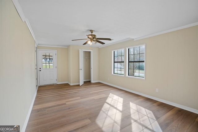 empty room with ornamental molding, ceiling fan, and light wood-type flooring