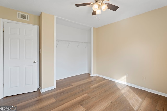 unfurnished bedroom featuring hardwood / wood-style floors, ceiling fan, and a closet