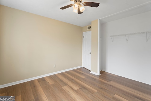 unfurnished bedroom with ceiling fan, wood-type flooring, and a closet