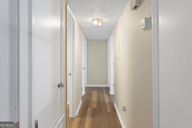 corridor with wood-type flooring and a textured ceiling