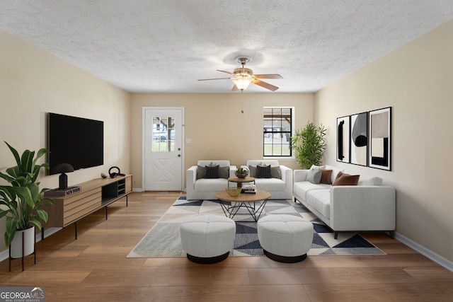 living room with ceiling fan, light hardwood / wood-style floors, and a textured ceiling