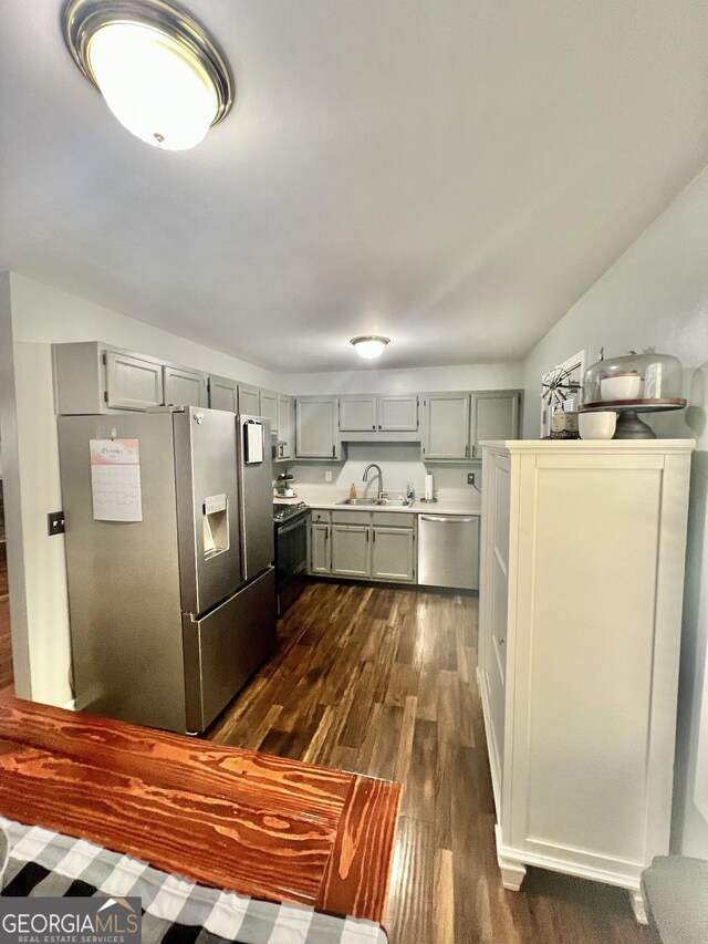 kitchen with dark wood-type flooring, stainless steel appliances, lofted ceiling, and sink