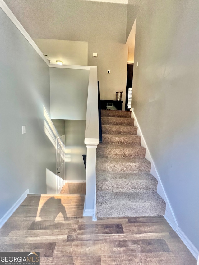 stairway with hardwood / wood-style floors, a textured ceiling, and crown molding