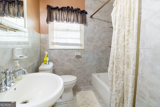 full bathroom featuring shower / bath combination with curtain, sink, tile patterned flooring, toilet, and tile walls