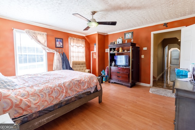 bedroom with ceiling fan, hardwood / wood-style floors, a textured ceiling, and ornamental molding