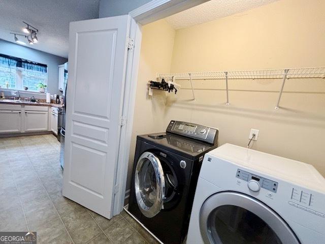 washroom featuring laundry area, light tile patterned floors, a textured ceiling, and independent washer and dryer