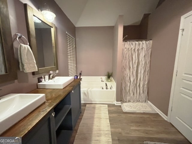 bathroom featuring vanity, wood-type flooring, vaulted ceiling, and shower with separate bathtub