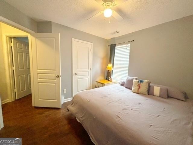 bedroom featuring dark wood-style flooring, visible vents, ceiling fan, a textured ceiling, and baseboards