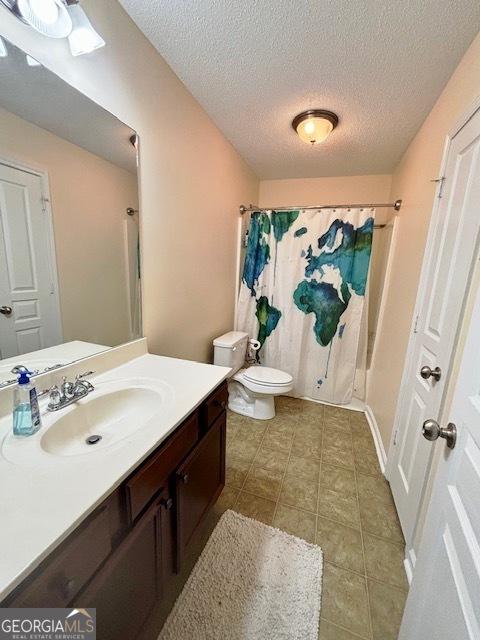 bathroom with tile patterned flooring, vanity, toilet, and a textured ceiling