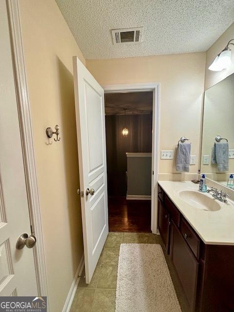 bathroom with tile patterned flooring, vanity, and a textured ceiling