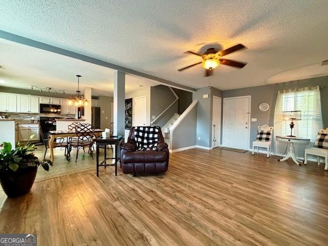 living room with ceiling fan, light hardwood / wood-style floors, and a textured ceiling