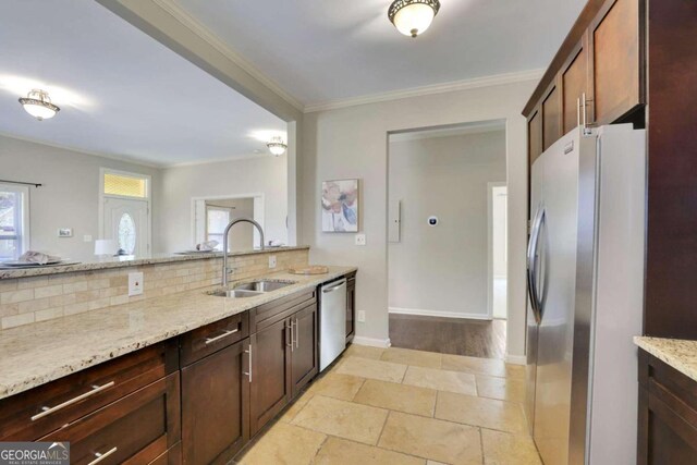 kitchen with sink, tasteful backsplash, light stone counters, appliances with stainless steel finishes, and ornamental molding