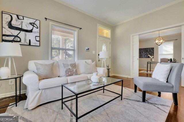 living room with hardwood / wood-style flooring, ornamental molding, and a notable chandelier