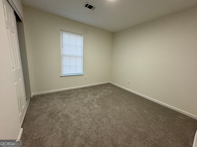 unfurnished bedroom with dark carpet and a closet