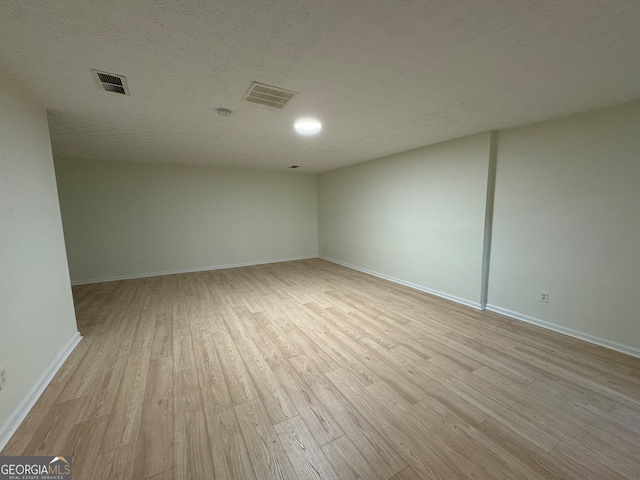 spare room featuring light hardwood / wood-style floors and a textured ceiling