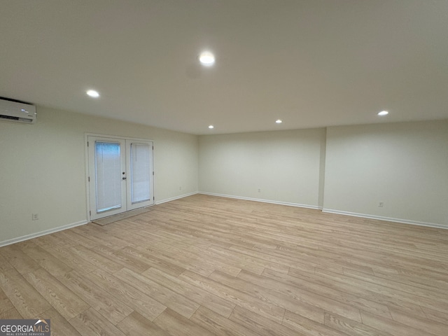 unfurnished room with french doors, light hardwood / wood-style flooring, and a wall mounted air conditioner