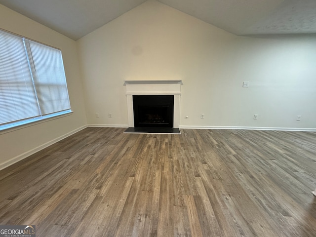 unfurnished living room featuring dark wood-type flooring and lofted ceiling