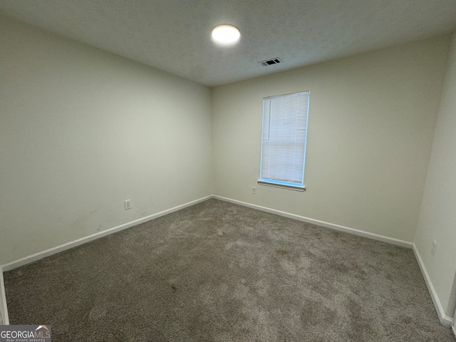 unfurnished room with dark carpet and a textured ceiling