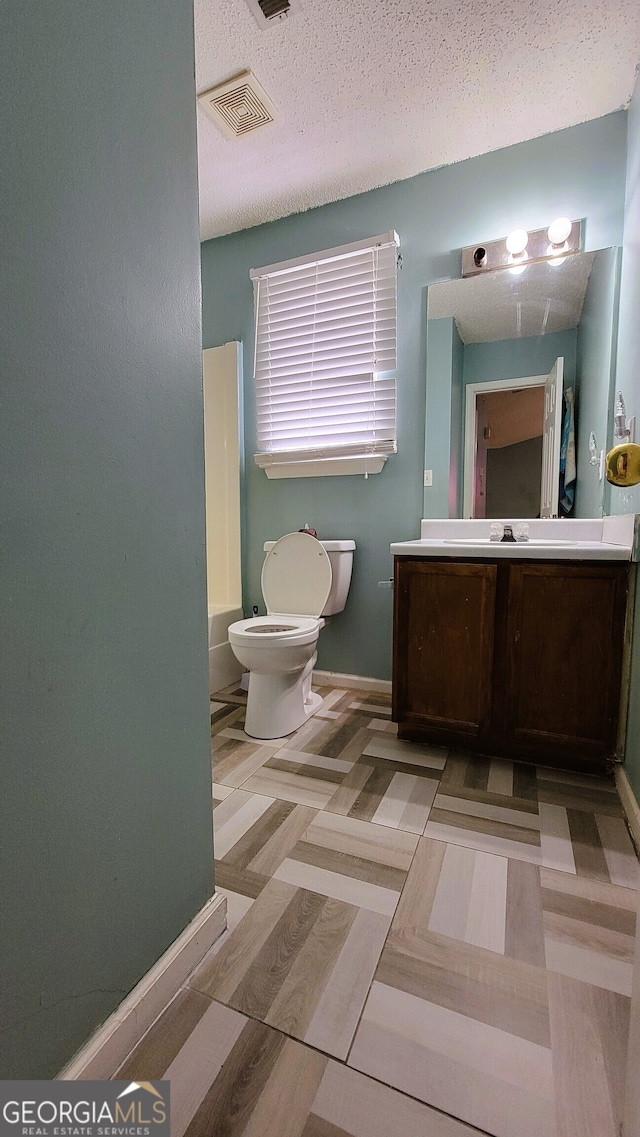 full bathroom featuring hardwood / wood-style floors, a textured ceiling, toilet, vanity, and shower / bathtub combination