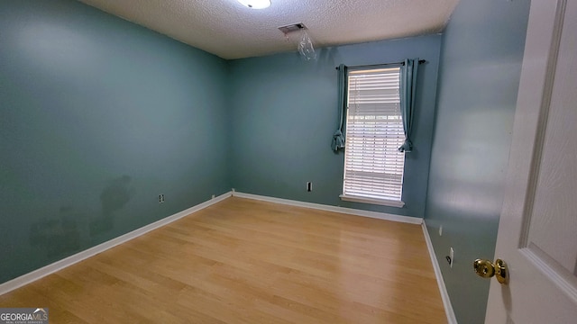 unfurnished room with a textured ceiling and light wood-type flooring