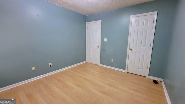 unfurnished room with a textured ceiling and light hardwood / wood-style flooring