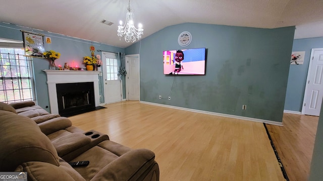 living room with wood-type flooring, an inviting chandelier, plenty of natural light, and lofted ceiling