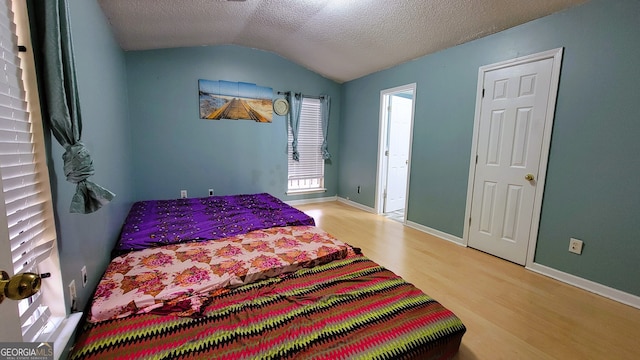 bedroom featuring a textured ceiling, lofted ceiling, and hardwood / wood-style flooring