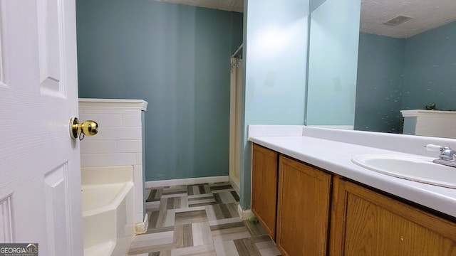 bathroom featuring a bathing tub, vanity, and a textured ceiling