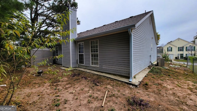 view of side of property featuring cooling unit and a storage shed