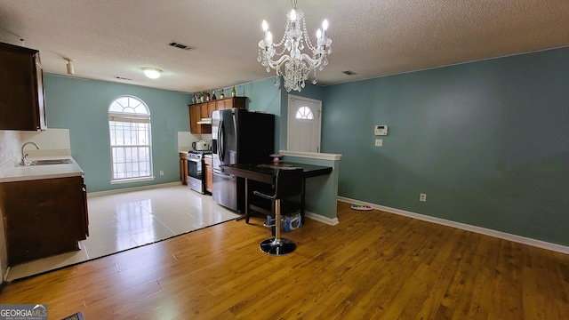 kitchen featuring sink, stainless steel appliances, a textured ceiling, and light hardwood / wood-style flooring