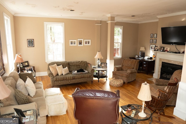 living room with ornate columns, wood-type flooring, and ornamental molding