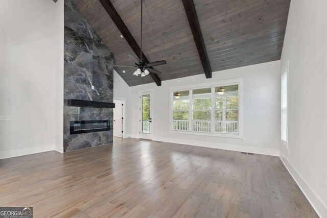 unfurnished living room with high vaulted ceiling, hardwood / wood-style flooring, a fireplace, beamed ceiling, and wood ceiling