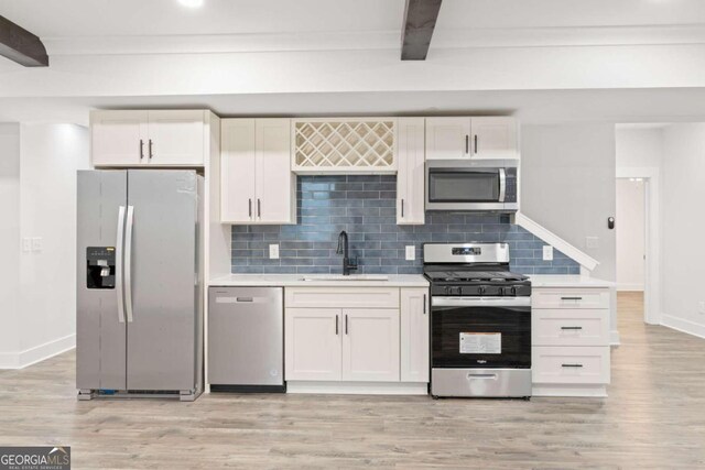 kitchen featuring white cabinets, beam ceiling, sink, and stainless steel appliances