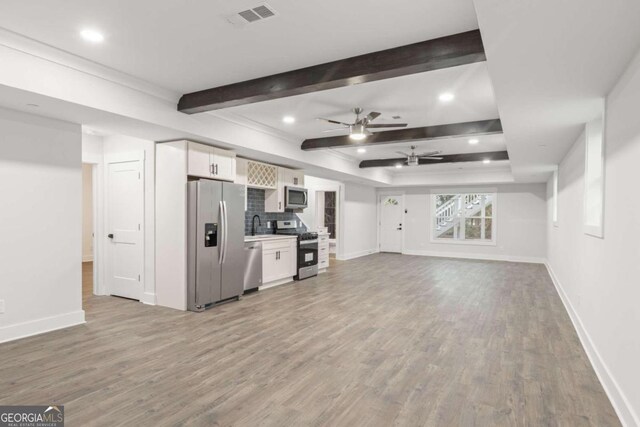 unfurnished living room with ceiling fan, beam ceiling, sink, and light hardwood / wood-style flooring