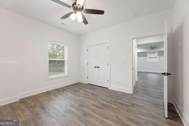 unfurnished bedroom with ceiling fan and dark wood-type flooring